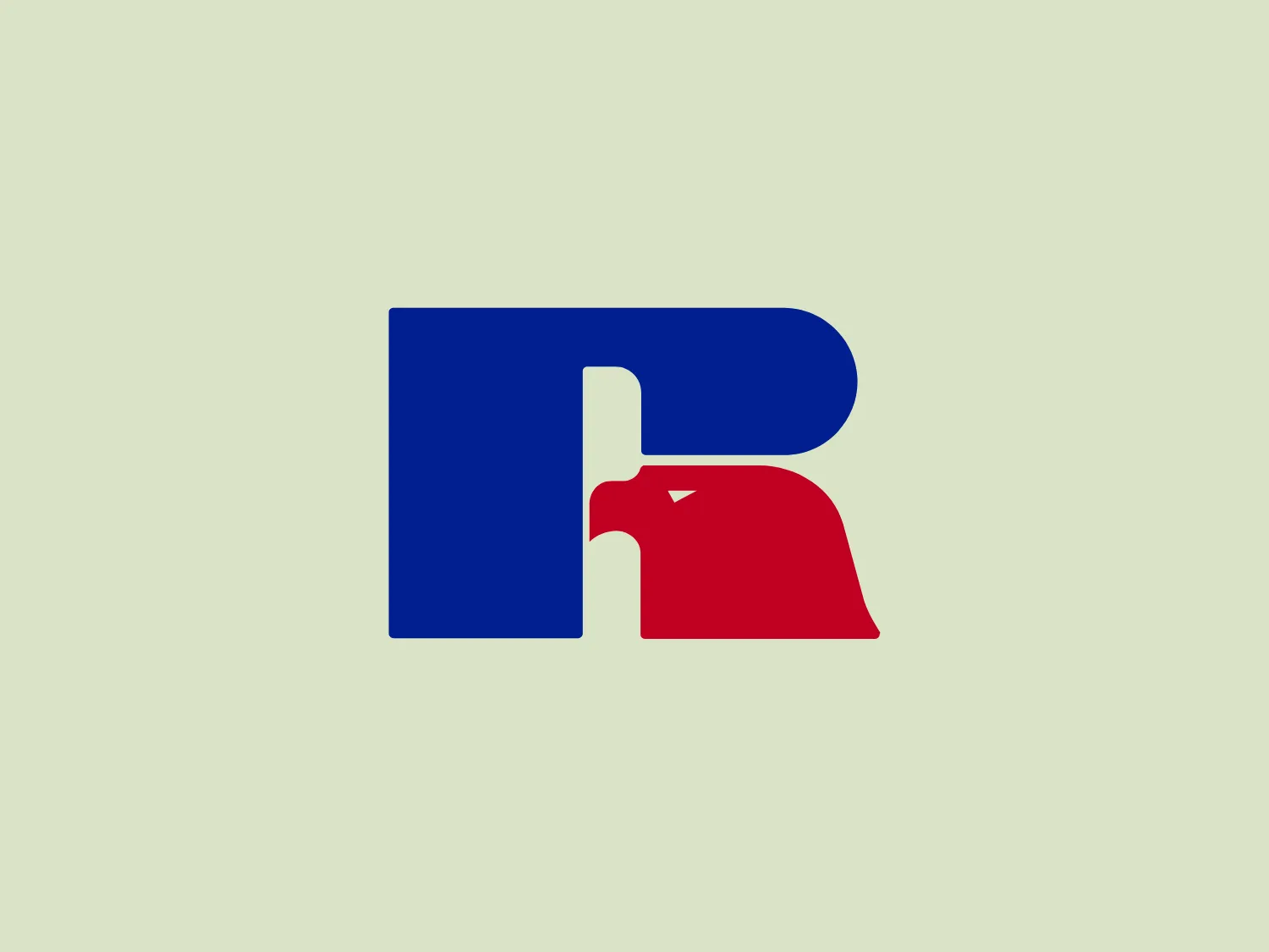 The Russell Athletic logo features a stylized letter "R" composed of two distinct parts with a dynamic design. The larger element is in a bold blue color, while the smaller section at the bottom right is in red. The design suggests a forward motion or a profile view of an object with a beak-like protrusion pointing rightwards. It is a simple yet effective use of negative space and color contrast to create a memorable and recognizable symbol. The minimal use of shapes gives it a modern and clean aesthetic.