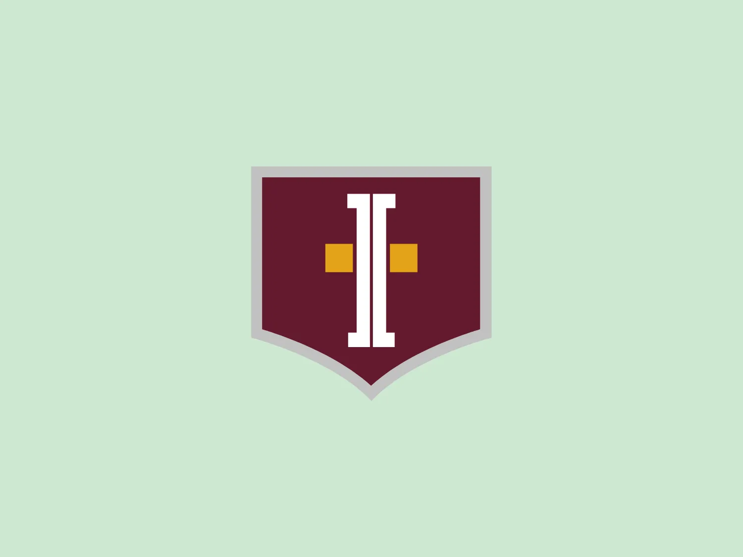 The School Incarnation logo showcases a shield-like shape with a deep maroon background. Positioned at the center is a stylized, modern letter "I" in a lighter shade, featuring a bold and blocky appearance. Small square accents in a rich yellow color flank the "I" on each side, providing contrast and drawing attention to the central letter. The overall design aesthetic is minimalistic and contemporary, with a limited color palette that conveys a sense of sophistication and strength.
