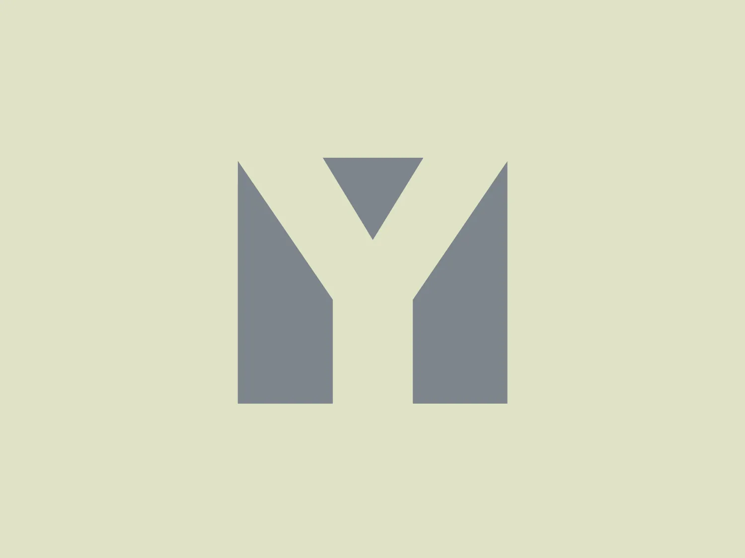 The Yarde Metals logo presents a stylized letter 'M' in a shade of medium grey. The design is minimalist and geometric, featuring sharp angles and clean lines. The upper part of the 'M' extends upwards into a centered triangular shape, giving the illusion of depth and adding a distinct feature to the overall design. The aesthetic is modern and appears to draw inspiration from flat design principles typically used in digital and technology-focused branding.