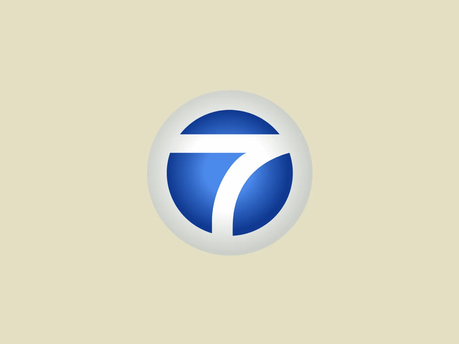 The image is a stylish and modern logo, consisting of a white circular background that encloses a design that looks like an abstract rendition of the number '7' for ABC 7. The design is made up of two bold, swooping elements, one above the other, creating a dynamic sense of movement. The color palette is a gradient of blues ranging from a deep, rich blue at the top to a lighter, more vibrant blue at the bottom. The white dividing line between the blue shapes is smooth and adds a sense of division or duality to the logo. The overall aesthetic is clean, fresh, and would be well-suited to a corporation or tech company.